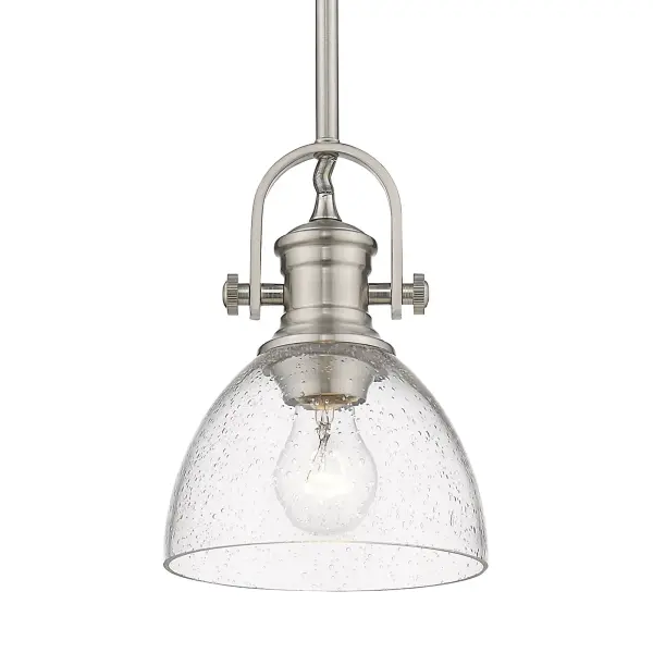 Bring Farmhouse elegance into your home with the Yep by Golden Lighting Hines 1-light 7in Pendant. Featuring a seeded glass shade and a Pewter frame, it creates a welcoming atmosphere. The seeded glass shade adds a touch of vintage character, featuring air bubbles that catch the light, creating a warm, inviting ambiance. Our Pewter finish offers a classic alternative with a rich, satin lustre, beautifully complementing both traditional and contemporary interiors. This pendant is perfect for focused illumination in entryways, foyers, and even bathrooms, and is rated for damp locations, making it suitable for covered and semi-enclosed spaces with occasional moisture. Installation is a breeze with its sloped-ceiling compatibility and adjustable height feature, allowing you to customize the hanging length between 11.75" and 53.75". Overall dimensions are 6.88"W x 9.13"H x 6.88"D, and it requires 1 E26 Medium base bulb (not included, maximum 100 watts). Elevate your decor with the timeless quality and charm of this pendant.
