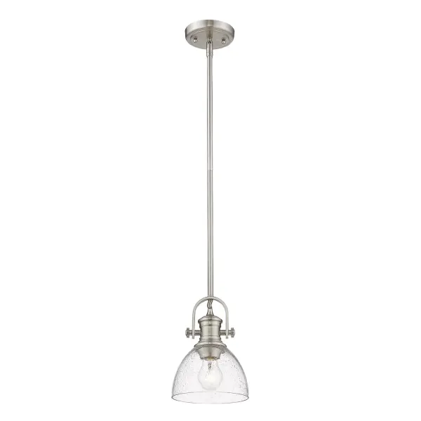 Bring Farmhouse elegance into your home with the Yep by Golden Lighting Hines 1-light 7in Pendant. Featuring a seeded glass shade and a Pewter frame, it creates a welcoming atmosphere. The seeded glass shade adds a touch of vintage character, featuring air bubbles that catch the light, creating a warm, inviting ambiance. Our Pewter finish offers a classic alternative with a rich, satin lustre, beautifully complementing both traditional and contemporary interiors. This pendant is perfect for focused illumination in entryways, foyers, and even bathrooms, and is rated for damp locations, making it suitable for covered and semi-enclosed spaces with occasional moisture. Installation is a breeze with its sloped-ceiling compatibility and adjustable height feature, allowing you to customize the hanging length between 11.75" and 53.75". Overall dimensions are 6.88"W x 9.13"H x 6.88"D, and it requires 1 E26 Medium base bulb (not included, maximum 100 watts). Elevate your decor with the timeless quality and charm of this pendant. - alternate view