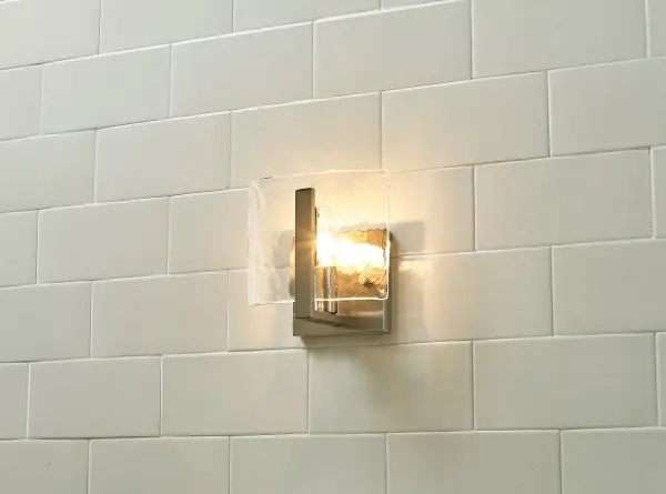 The Aenon wall sconce combines artisan craftsmanship with practical illumination. Its hammered water glass shade creates a stunning flowing water effect, while the pewter finish adds understated warmth suitable for both traditional and contemporary spaces. - alternate view