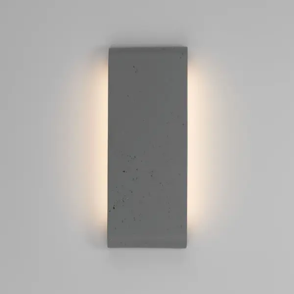 The Golden Lighting Stela 16" Integrated LED Outdoor Wall Light presents a modern architectural design inspired by natural stone. Its gently curved profile and travertine-textured surface create a sculptural presence while maintaining a clean, contemporary silhouette. The integrated linear LED light source is discreetly recessed, producing soft, ambient illumination that enhances the fixture's form without visual clutter. Finished in Gray Travertine, the surface showcases subtle mineral texture, delicate pitting, and a smooth matte sheen that evokes the refined character of honed stone. Measuring 16"W x 6.25"H x 1.75"D, this fixture is ideal for entryways, patios, garage exteriors, and architectural facades. Wet-location rated for direct exposure to the elements, it delivers 750 lumens at 3000K for warm, energy-efficient outdoor illumination. Collection: Stela Finish: Gray Travertine Width: 16.00" Height: 6.25" Weight: 6.30 lb Extension from Wall: 1.75" Canopy: 14"W x 3"H x 0.5"D Bulbs Included Number of Bulbs: 1 Maximum Wattage: 11.00 W Bulb Type: Panel Light Source: LED Dimmable Voltage: 120.00 V Country of Origin: China Safety Listing: ETL ADA LED Manufacturer Warranty: 5 Year Limited