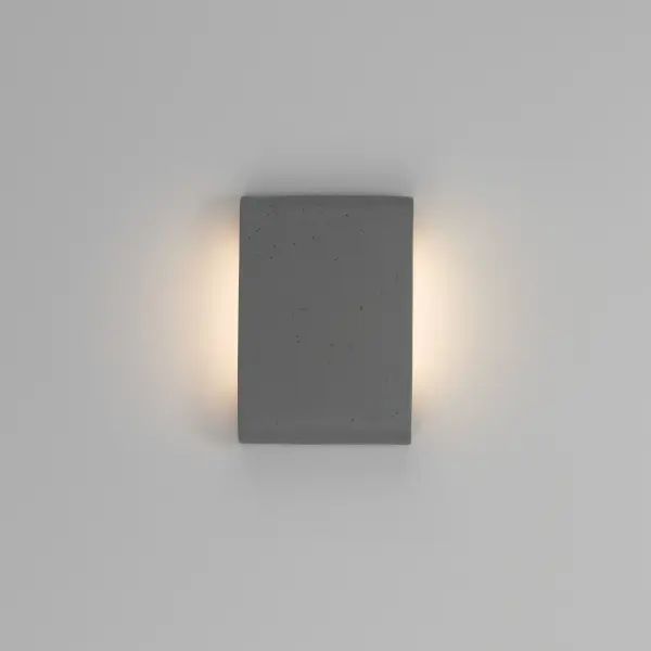 The Golden Lighting Stela 9" Integrated LED Outdoor Wall Light offers a refined architectural lighting solution inspired by natural stone forms. Crafted from concrete with a gently curved profile, this compact fixture features a gray travertine finish with subtle pitting and mineral variation that evokes the look of honed stone. A discreetly recessed linear LED light source provides soft, even illumination that enhances the fixture's sculptural silhouette without visual clutter. Measuring 8.75"W x 6.25"H x 1.75"D, the Stela 9" is ideal for entryways, patios, garage exteriors, and architectural accent walls. Wet-location rated for full outdoor exposure, it delivers 530 lumens at a warm 3000K color temperature, combining durability, energy efficiency, and understated modern elegance. Collection: Stela Finish: Gray Travertine Width: 8.75" Height: 6.25" Weight: 4.10 lb Extension from Wall: 1.75" Canopy: 7"W x 3"H x 0.5"D Bulbs Included Number of Bulbs: 1 Maximum Wattage: 7.00 W Bulb Type: Panel Light Source: LED Dimmable Voltage: 120.00 V Country of Origin: China Safety Listing: ETL ADA LED Manufacturer Warranty: 5 Year Limited