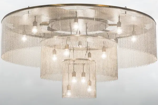 Like the gentle flow of a water fountain with tiny droplets dancing in mid-air; you can almost hear the pitter-patter as it creates soft ripples in the imaginary pool below. Beautiful ambient light evokes from 16 customer supplied lamps embraced from three tiers of this lovely ceiling fixture. Antique Copper powder coated hardware is enhanced with graceful veils of Stainless Steel ball chains. Handcrafted in our 180;000 square foot manufacturing facility in Yorkville; New York. Available in custom sizes and finishes. UL and cUL listed for damp and dry locations.