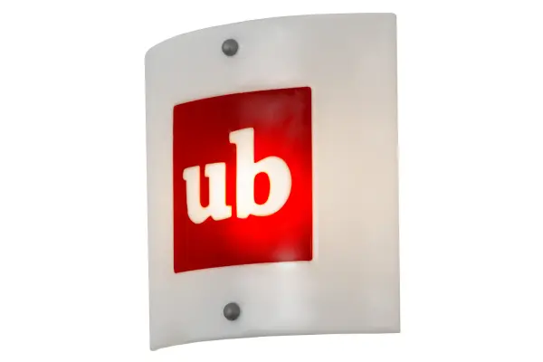 Hot high-fired glass is transformed into a cool abstract lighting design, blending the bold UB logo on Red art glass over a White glass background. Striking fused glass defines this extraordinary wall sconce, which is ideal for illuminating a wide range of rooms in business offices. The Personalized UB Logo Wall Sconce is included in the American-made, American-designed, handcrafted Personalized Collection and manufactured in Yorkville, New York. This ADA-compliant is UL and cUL listed for dry and damp locations. Please provide us with your logo or initials so we can develop a lighting fixture for your next project. Call us for pricing and lead time. Collection: Metro Fusion Finish: Nickel Glass: White Glass/Red Ub Logo Width: 11.00" Height: 11.00" Length: 3.00" Weight: 4.00 lb Extension from Wall: 3.00" Number of Bulbs: 1 Maximum Wattage: 60.00 W Bulb Type: T10 Bulb Base: E26 Material: Steel Country of Origin: USA Safety Listing: Damp Safety Rating: Damp