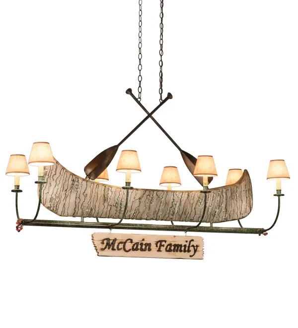 This handsome 8-light chandelier; complete with Antique Copper finished steel paddles; is the perfect complement to your camp; home; lodge; or cabin. McCain Family is custom engraved with a hot iron branding on the attached signage. This charming fixture features a faux birch bark Canoe; surrounded by eight curved arms with Parchment shades that top Ivory faux candlelights on bobeches. The hardware includes Tarnished Copper finished arms and frame. The overall height ranges from 42 to 84 inches; as the chain can be easily adjusted in the field. The Personalized Canoe 8 Light Chandelier is featured in our American-made; American-designed; handcrafted Personalized Lighting Collection. UL and cUL listed for dry and damp locations; however; we do not recommend placing it in spaces that experience a large amount of moisture due to the parchment shades. Please provide us with your family name so we can develop lighting fixtures that bring joy and pride to your home. Call us for pricing and lead time.