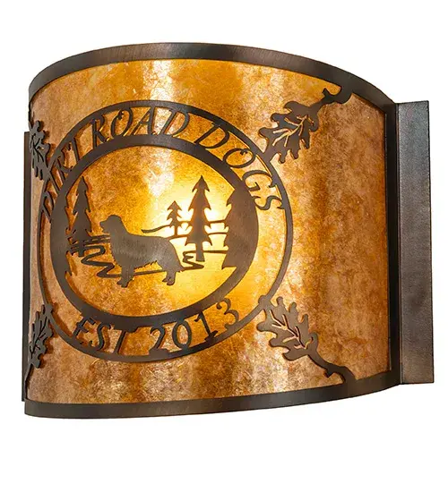 A stunning curvaceous wall sconce is personalized with the DIRT ROAD DOGS EST 2013 logo and graphics. A Dog stands among the Tall Pine trees across the perimeter of the shade; adorned with Oak leaves on the corners. Soft ambient light is diffused beautifully through the Amber Mica lens; which is complemented by an appealing frame and hardware featuring a Dark Burnished Antique Copper finish. The Personalized Dirt Road Dogs Wall Sconce is included in our American-made; American-designed; handcrafted Personalized Collection and manufactured in Yorkville; New York. The fixture is UL and cUL listed for dry and damp locations. This lighting fixture can be ordered by calling us and adding your own business or camp name for your next project. Please call for pricing and lead time. - alternate view