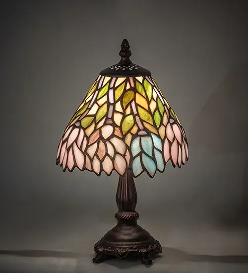 The Wisteria lamp features cascading blossoms in variegated hues of Blue, Pink and Purple art glass that are accented with Spring Green leaves. Designed with an undulating border, this beautiful art glass shade offers a complex artistic pattern that is complemented with an exquisite base in a Mahogany Bronze finish. Custom colors, styles, sizes and bulb options are available. UL and cUL listed for dry locations. Collection: Wisteria Finish: Mahogany Bronze Glass: Stained Glass Width: 7.00" Height: 13.00" Length: 7.00" Weight: 2.00 lb Number of Bulbs: 1 Maximum Wattage: 60.00 W Bulb Type: B10 Bulb Base: E12 Material: Zinc Country of Origin: CHINA Safety Listing: Dry Safety Rating: Dry