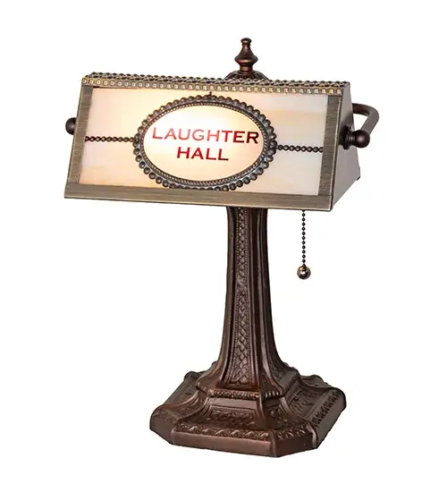 Designed with the Laughter Hall and logo; this handsome art glass shade illuminates an office interior while featuring the artwork in Red on a Beige Art Glass background; complemented by a Hi-Lited Craftsman Brown finish and a banker's lamp base in Mahogany Bronze. The Personalized Laughter Hall Construction Table Lamp is included in our American- made; American-designed; handcrafted Personalized Lighting Collection and manufactured in Yorkville; New York. The lamp is UL and cUL are listed for dry locations. This art glass shade can be ordered; and we will coordinate the custom logo with you to suit your project. Call for pricing and lead time. - alternate view