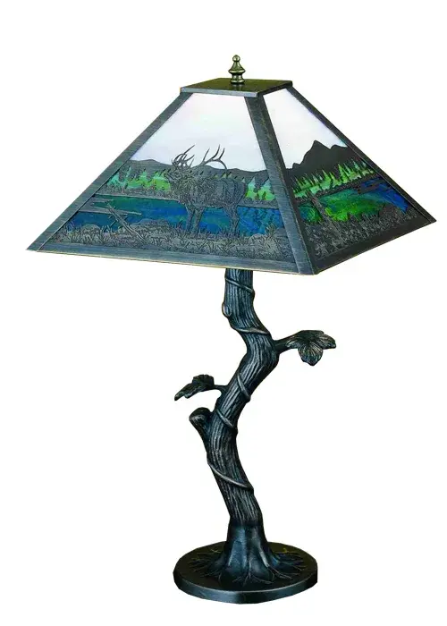 An Elk wanders by a lake in the woods on this nature inspired etched brass lamp shade. The table lamp; with Apple Tree base; is finished in Mahogany Bronze with Dawn Sky Blue; Blue and Green stained art glass panels. The lamp is handcrafted in the USA by Meyda artisans.