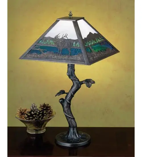 An Elk wanders by a lake in the woods on this nature inspired etched brass lamp shade. The table lamp; with Apple Tree base; is finished in Mahogany Bronze with Dawn Sky Blue; Blue and Green stained art glass panels. The lamp is handcrafted in the USA by Meyda artisans. - alternate view