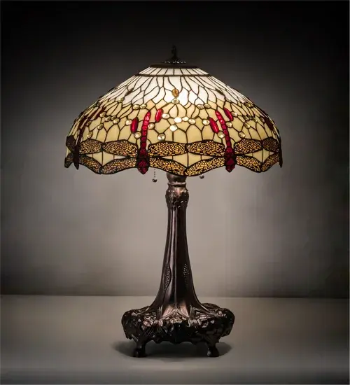 Scarlet dragonflies with glowing jeweled eyes and filigree topped amber wings, dive over a Bone Beige background dappled with Red, Clear and Amber jewels. This art glass shade is created using the famous Meyda Tiffany copperfoil construction and complemented with an elegant cast metal footed base finished in Mahogany Bronze. The Tiffany Hanginghead Dragonfly Mini Lamp is featured in our American designed, handcrafted Tiffany Reproduction Stained Glass Lighting Collection. UL and cUL listed for dry locations. Each shade is a unique work of art with color variations based on natural ingredients inherent in the glass. Contact us if color matching is critical when ordering multiple items. Collection: Tiffany Hanginghead Dragonfly Finish: Mahogany Bronze Glass: Ba Fl Width: 22.00" Height: 31.00" Length: 22.00" Weight: 17.50 lb Number of Bulbs: 3 Maximum Wattage: 60.00 W Bulb Type: A19 Bulb Base: E26 Material: Steel/Zinc Country of Origin: CHINA Safety Rating: Dry