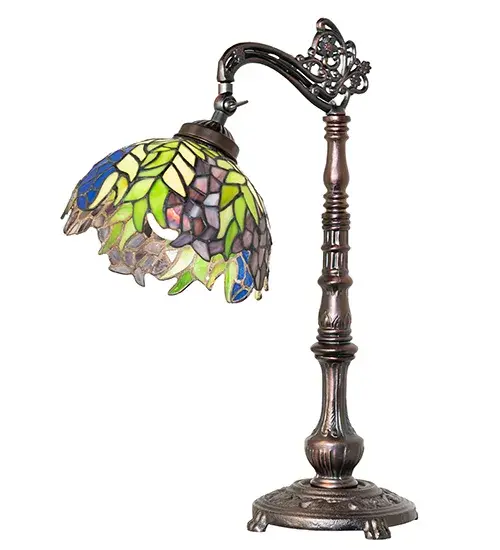 The Honey Locust was a popular floral design created by Louis Comfort Tiffany over a century ago. Decorative dome-shaped stained glass lampshades with petal-shaped edges depict clusters of Plum and Periwinkle flowers amid Spring Green leaves cascading towards the base. This table lamp features an elegant cast metal bridge arm base finished in Mahogany Bronze. Ideal for illuminating tables and desks in homes; banks; and libraries from Scottsdale; Arizona; to Billings; Montana; to Seattle; Washington. The Tiffany Honey Locust Bridge Arm Table Lamp is included in our American-designed; handcrafted Tiffany Stained Glass Collection. UL & cUL listed for dry locations. Each shade is a unique work of art with color variations based on natural ingredients inherent in the glass. - alternate view
