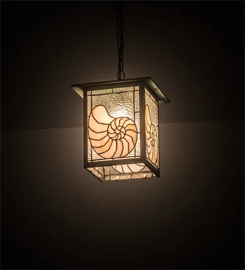 An ocean Nautilus shell is depicted on this sea inspired lantern pendant. The fixture is finished in a Verdi washed Copper; has Beige and Clear textured art glass panels; and is handcrafted in the USA by Meyda artisans.