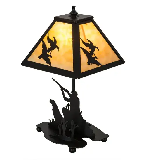 This striking lamp design features silhouettes of a sportsman hunting duck in the woods with a trusty dog by his side. Beautiful ambient light projects through the Beige art glass shade featuring Ducks in flight design and perched on the accent lamp base. The decorative accents, frame and base are featured in a bold Black Textured finish.Handcrafted by skilled artisans in our manufacturing facility at the foothills of the Adirondack Mountains, the lamp is available in custom designs, sizes and styles. Energy efficient lamping options are available.This indoor accent is UL and cUL listed for dry locations. Collection: Duck Hunter Finish: Textured Black Textured Black Glass: Beige Art Glass Width: 11.00" Height: 15.00" Length: 8.00" Weight: 3.50 lb Number of Bulbs: 1 Maximum Wattage: 60.00 W Bulb Type: B10 Bulb Base: E12 Material: Metal Or Polyresin Country of Origin: USA Safety Listing: Damp Safety Rating: Damp - alternate view