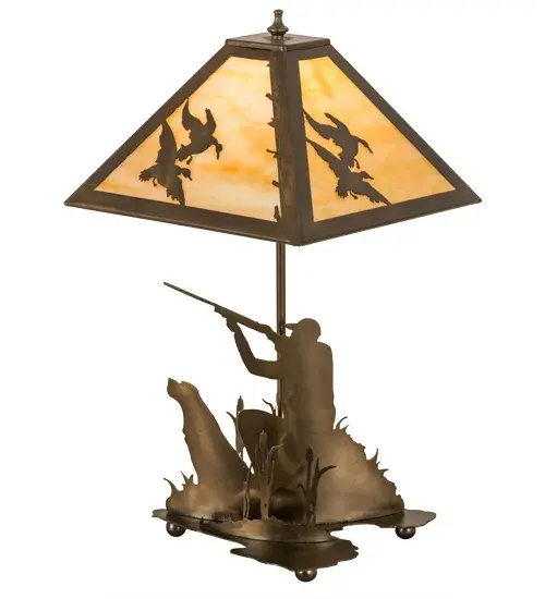 This striking lighting design features silhouettes of a sportsman hunting in the woods with a trusty dog by his side on the decorative base while ducks in flight are depicted in the shade design. Beautiful ambient light projects through Beige art glass which is complemented with a steel frame and hardware featured in an Antique Copper finish.A 3-section switch lights up the shade; base or both.Handcrafted by highly skilled artisans in our manufacturing facility at the foothills of the Adirondack Mountains; this lamp is available in custom designs; sizes and styles. Energy efficient lamping options such as LED are available.The lamp is dry listed for interior use. - alternate view