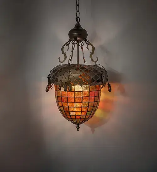 Majestic as the mighty oak is this leaf adorned inverted pendant in an antique copper finish. A lighted stained glass acorn; in multi toned Autumn Green with a Bark Brown granite glass crown sprouting oak leaf covered hardware that is hand made in the USA by Meyda Tiffany craftsmen.
