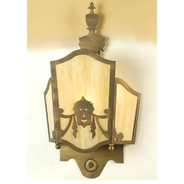 The Theatre Mask Wall Sconce features an appealing Gothic Revival look and is designed with three panels of Clear Opaque Beige art glass. The shade's decorative accents depict a theatrical player's mask and its accents and frame are hand- finished in a handsome Antique Brass. Collection: Theatre Mask Finish: Horizontal Even Grindmarks Glass: Antique Copper Ba Width: 12.00" Height: 21.00" Length: 4.25" Weight: 4.50 lb Extension from Wall: 4.25" Number of Bulbs: 1 Maximum Wattage: 60.00 W Bulb Type: A19 Bulb Base: E26 Material: Steel Country of Origin: USA Safety Listing: Dry Safety Rating: Dry