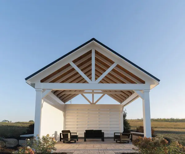 Experience the epitome of outdoor grandeur with our Wellington Pavilion. Meticulously crafted for enduring beauty and structural excellence, this pavilion redefines alfresco living, offering a stunning focal point for your gatherings and creating an ambiance of timeless sophistication in your outdoor space. Standard Model Includes: • Pressure treated wood wrapped with cellular PVC • Paintable • 8×8 posts • 8/12 pitch roof • Painted rafters with exposed pine sheathing • 12" overhang - alternate view