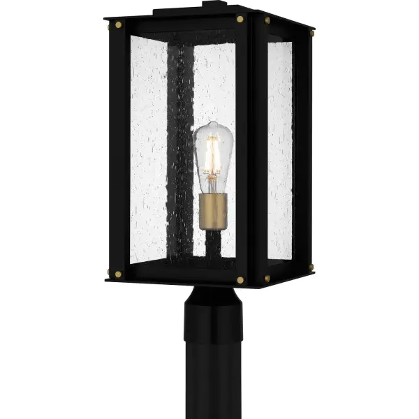 The Robbins post mount combines timeless lantern styling with industrial details and coastal-grade construction. Gold accents add warmth to the matte black frame, while seedy glass creates ambient illumination perfect for outdoor spaces.
