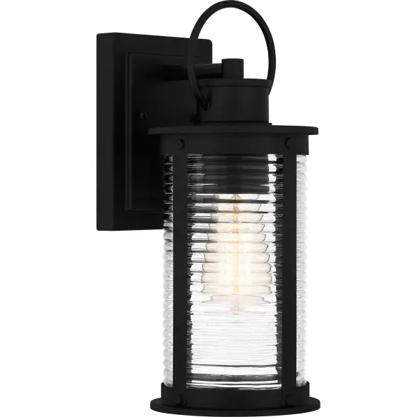 Tilmore outdoor lanterns are the perfect companion to coastal-inspired exteriors. The sturdy matte black frame is accentuated by clear ribbed glass for a classic look, designed to withstand the elements in style. Available as a hanging lantern, post lantern, and various sizes of wall lantern, Tilmore is an easy way to illuminate a front porch or landscape.