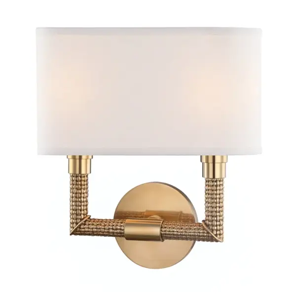 The Dubois wall sconce combines aged brass warmth with crisp white linen shades for a sophisticated look. Its compact 11.5-inch width makes it ideal for flanking mirrors or creating symmetrical lighting in smaller spaces.