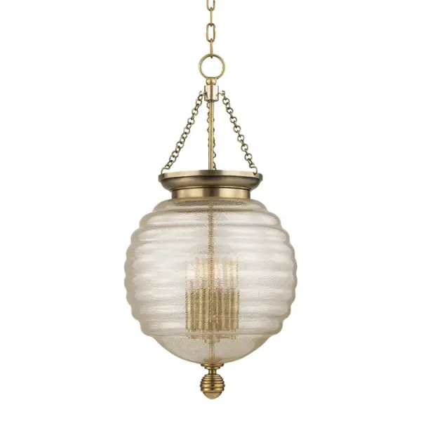 The Coolidge pendant showcases exceptional craftsmanship with its signature beehive-shaped spun glass diffuser wrapped in brass mesh. The aged brass finish and spherical cast metal details create a sophisticated focal point that bridges traditional and contemporary aesthetics.