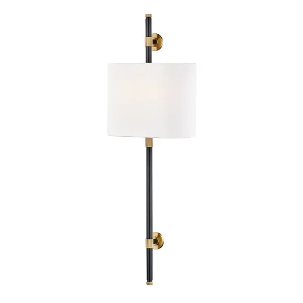 The Bowery wall sconce makes a bold vertical statement at 34 inches tall, combining aged bronze metalwork with white linen shades. Its substantial presence and traditional styling work beautifully in spaces with high ceilings or where dramatic impact is desired.