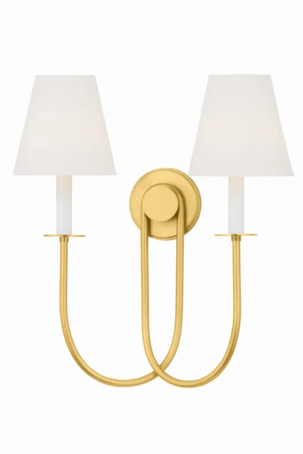 The Midtown sconce masterfully bridges traditional and modern aesthetics with its streamlined backplate and gracefully looping arms. The white linen shades soften the Aged Brass finish, creating a versatile fixture that elevates bathrooms, bedrooms, and hallways with timeless appeal.