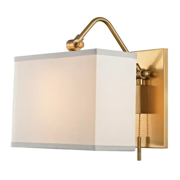 The Leyden wall sconce combines aged brass metalwork with a soft fabric drum shade, creating warm ambient lighting. Its compact 9-inch profile and pull-chain operation make it ideal for bedrooms and hallways.