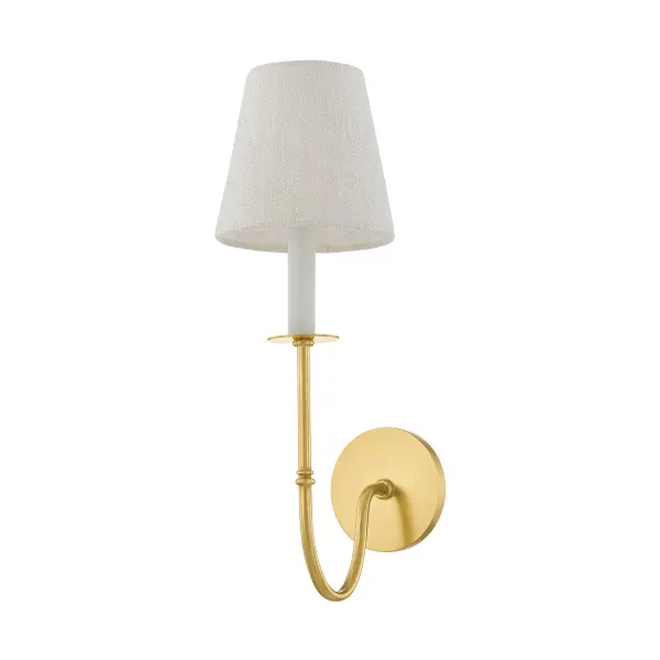 The Amina wall sconce masterfully bridges traditional Victorian metalwork with contemporary styling. Its elongated J-arm in aged brass creates dramatic visual interest, while the white linen shade softens the look for versatile placement.