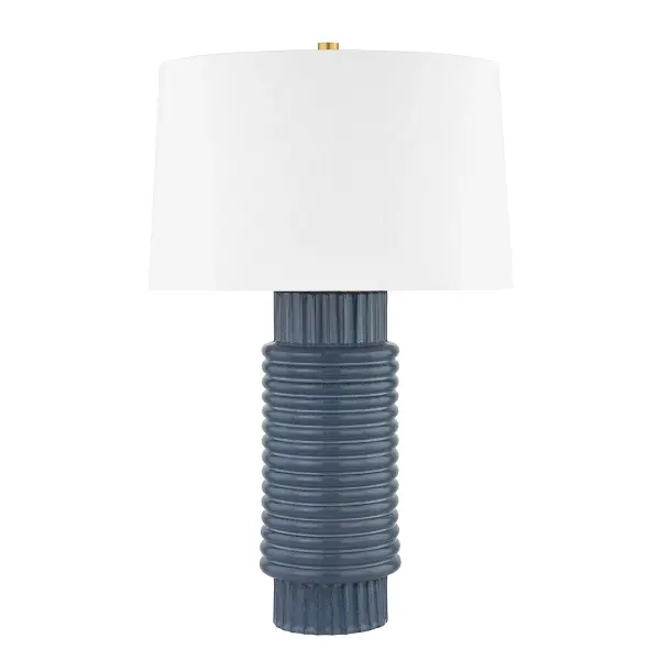 This sophisticated table lamp combines a reactive grey-blue ceramic base with warm aged brass hardware, creating a refined transitional aesthetic. The artisanal ceramic finish ensures each piece is unique.