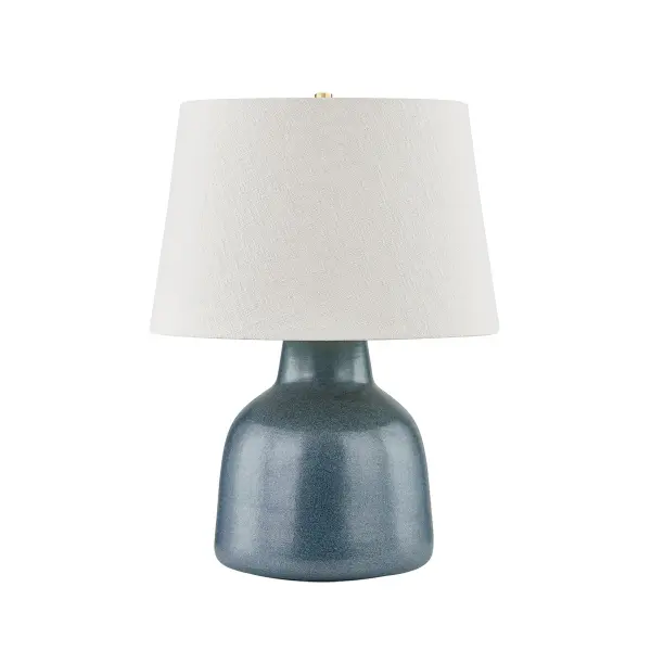 This elegant table lamp combines aged brass metalwork with a textured navy ceramic base, creating a refined transitional piece that bridges traditional and contemporary aesthetics with coastal charm.