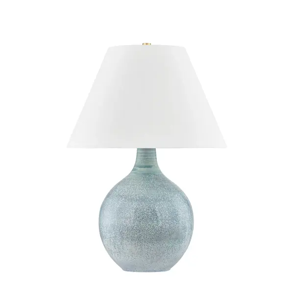 This distinctive table lamp features a reactive glaze ceramic base in seaglass tones paired with aged brass accents. The artisanal finish ensures each piece is unique, bringing organic texture and coastal sophistication to any space.