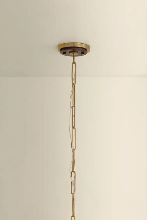 The Scheana pendant merges stem and shade into a single sculptural form carved from solid wood. Its rippled surface with concentric rings creates a tactile play of light and shadow, while the Aged Brass chain adds refined contrast. - alternate view