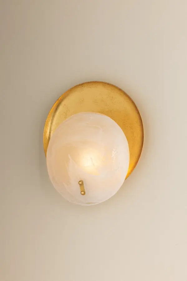 The Shanette Wall Sconce combines artistry with functionality through its distinctive Piastra glass shade featuring soft white swirls. The Vintage Gold Leaf finish and metal reflector create depth and warmth, making it a sophisticated choice for any interior. - alternate view