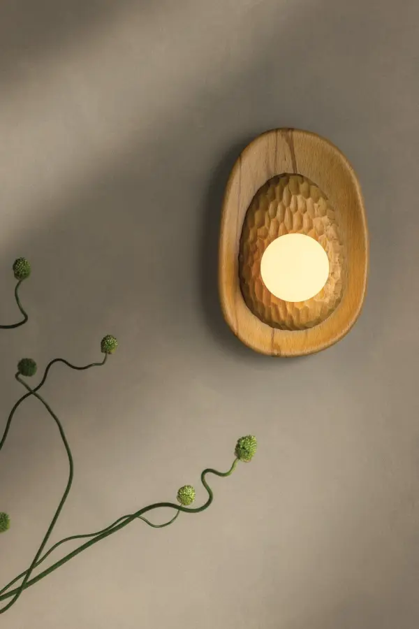 Defined by its sculptural, oblong silhouette and layered construction, the Pres wall sconce brings a sense of heritage craftsmanship to a compact space. The chiseled wood detailing juxtaposes the smooth beech wood reflector dish, creating an intriguing sense of depth. An exposed bulb draws attention to the natural grain and artisanal texture of the wood, while an Aged Brass cuff lends a subtle note of shine to the sconce’s profile. Part of our Hilary Matt x Mitzi Tastemakers collection. *Due to the one-of-a-kind nature of the medium, exact colors and patterns may vary slightly from the image shown. - alternate view