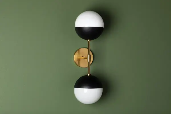 The Renee Wall Sconce combines aged brass warmth with black accents for a sophisticated look. Its compact design and glass globe shade make it perfect for bathrooms, hallways, and intimate spaces seeking refined illumination. - alternate view