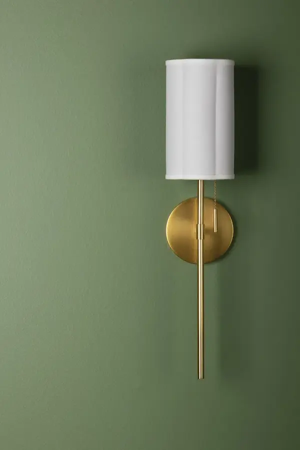 The Fawn Wall Sconce combines sleek sophistication with subtle feminine touches. Its scalloped fabric shade and aged brass pull chain create a refined look that works beautifully in traditional and contemporary spaces alike. - alternate view
