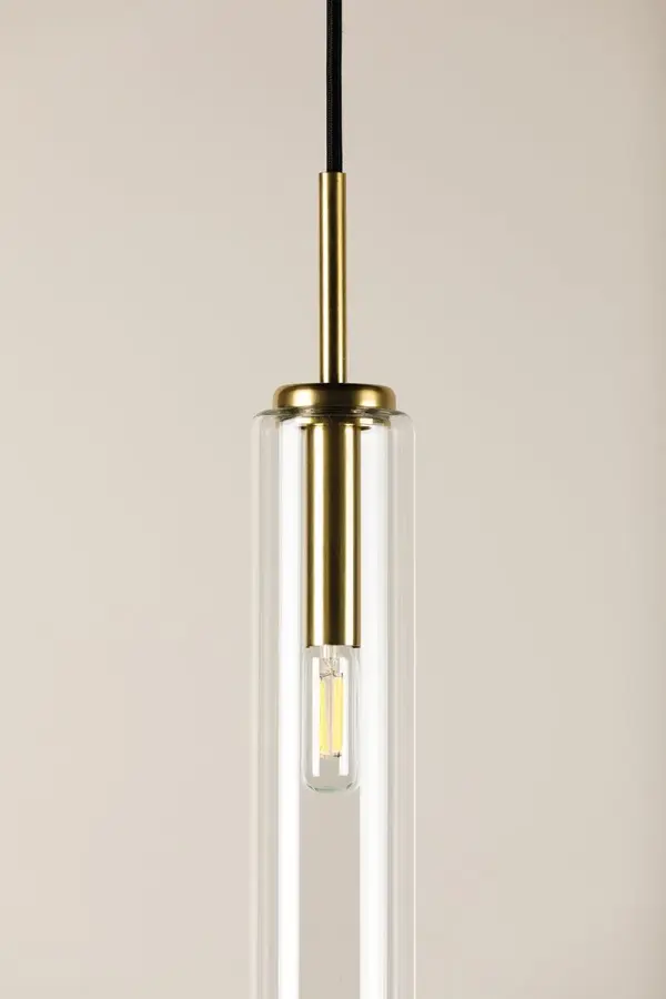 The Nyah Large Pendant combines contemporary minimalism with elevated proportions. Its oversized tubular glass shade creates a striking focal point while the aged brass socket adds subtle warmth and sophistication. - alternate view