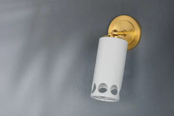 The Jean Wall Sconce combines classic aged brass finish with clear glass for a sophisticated lighting solution. Its compact design and transitional style make it versatile for various interior settings. - alternate view