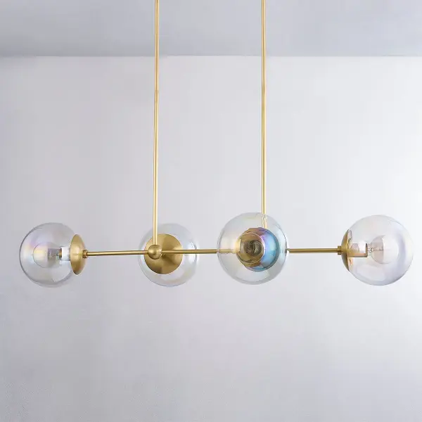 The Ophelia Island Light combines aged brass with iridescent glass globes for an otherworldly aesthetic. Its linear design brings softness and contemporary style to kitchen islands and dining spaces. - alternate view