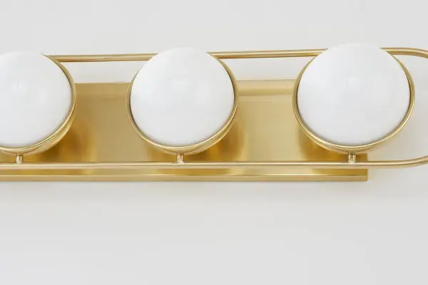 The Amy Bath and Vanity Light brings a sophisticated jewelry aesthetic to bathroom spaces with opal glass spheres set in an elegant Aged Brass racetrack frame. Versatile vertical or horizontal mounting makes it perfect above or alongside mirrors. - alternate view