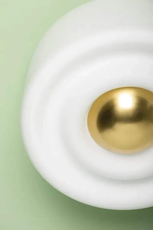 The Ciela Flush Mount combines artistic design with functional lighting through its deeply grooved opal glass shade that creates ripple-like patterns. The oversized dome finial adds sculptural interest while the aged brass finish provides warmth. - alternate view