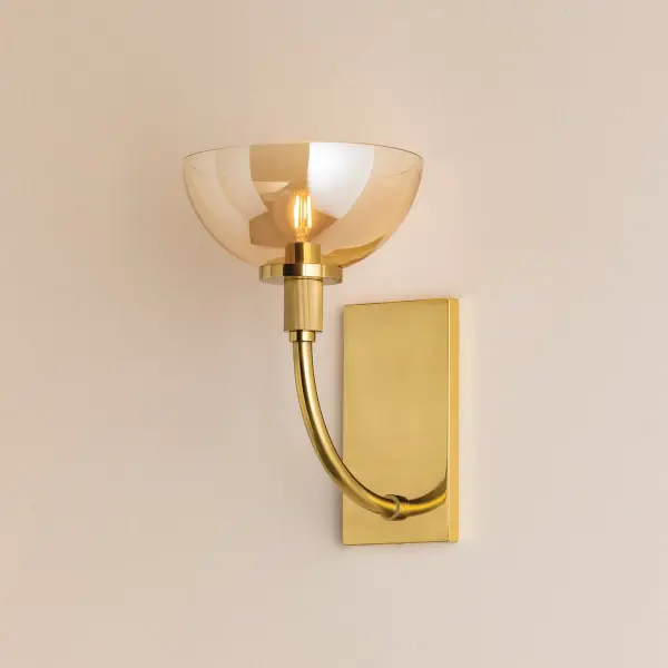 The Eva Wall Sconce combines spare sculptural design with luxurious materials. Aged Brass arms sweep upward to support bronze-plated glass shades, while fluted socket cups add textural interest. Perfect for bridging traditional and contemporary aesthetics.