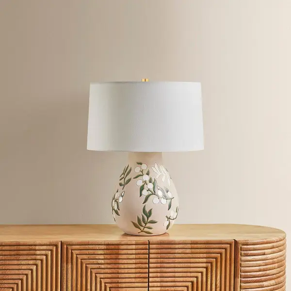 The Maeve table lamp combines artistic craftsmanship with functional lighting. Its hand-painted floral motif in soft pastels creates a unique, vase-like aesthetic, while the white linen shade provides warm, diffused illumination. - alternate view