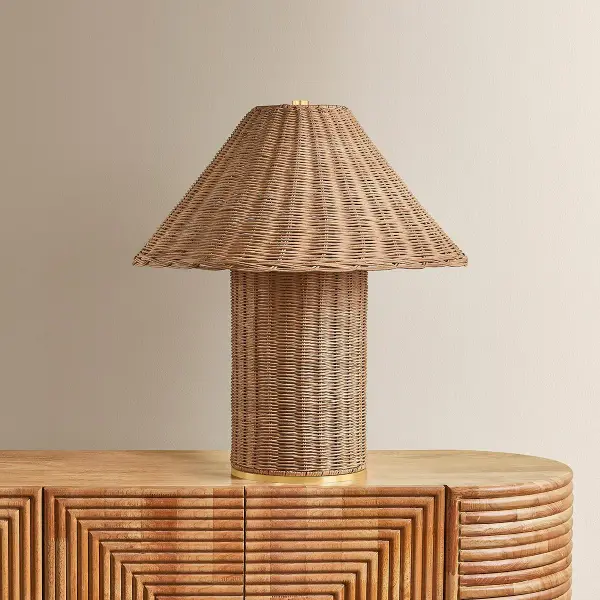 The Jeanette table lamp combines natural woven wicker with aged brass accents for a bold, textural statement. Its sculptural silhouette and handcrafted appeal make it perfect for adding warmth and organic charm to bedrooms, living spaces, or offices. - alternate view