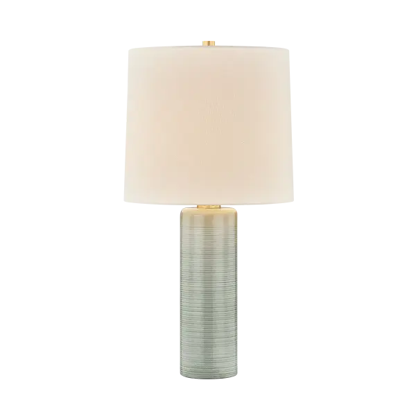The Tuva table lamp combines minimalist form with artisanal craftsmanship. Its tall cylindrical ceramic base features a distinctive pale blue Silver Lake glaze with horizontal ribbing that creates subtle depth and texture.