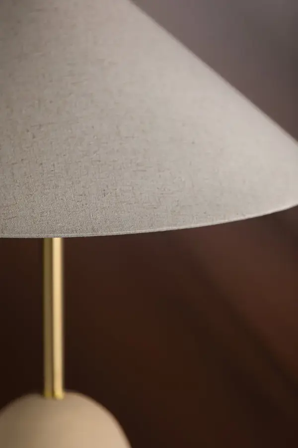 The Maia Table Lamp is a stunning fusion of cultural influences, featuring a mountain-inspired ceramic base and Korean roof-line shade. Its natural neutral palette with aged brass accents creates an intimate yet intriguing focal point. - alternate view