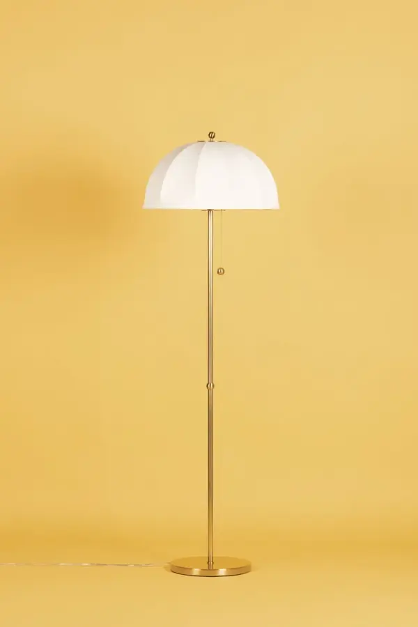 The Meshelle Floor Lamp brings playful mid-century charm with its distinctive umbrella-shaped shade. Light flows through and around the shade creating ambient glow, while aged brass finials and chain details add refined sophistication. - alternate view