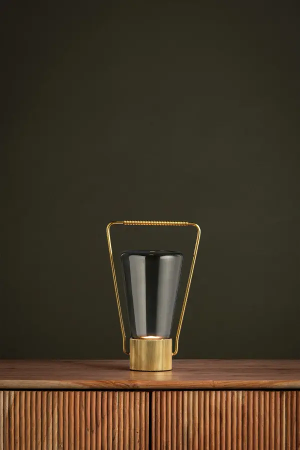 The Booker rechargeable table lamp reimagines the classic lantern with a modern twist. Its petite size, smoke glass shade, and aged brass frame create a moody aesthetic perfect for smaller spaces. The tactile handle makes it easy to move. - alternate view