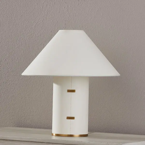 The Bond Table Lamp combines natural parchment wrapping with sophisticated brass accents for a relaxed yet elevated aesthetic. Its stitch detailing and clasp-like hardware add artisanal character while the tapered shade creates warm, ambient lighting. - alternate view